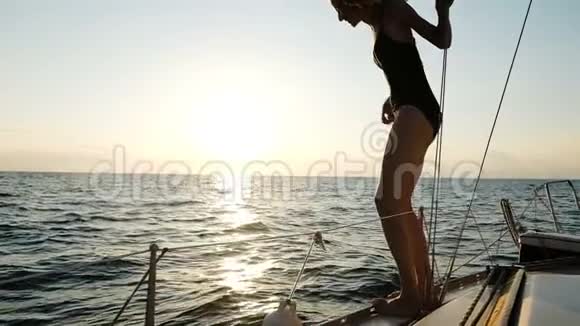 夕阳西下瘦漂亮的女孩从游艇上跳入开阔的大海慢动作视频的预览图