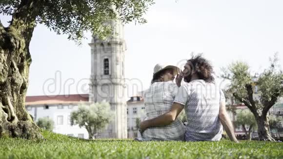 一对情侣在公园草地上的树旁接吻视频的预览图