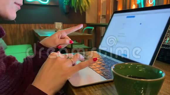 一个女人坐在咖啡馆里用她的笔记本电脑滚动网站页面视频的预览图