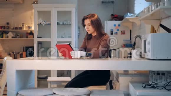 一个有假肢的女人正在厨房里用平板电脑工作视频的预览图