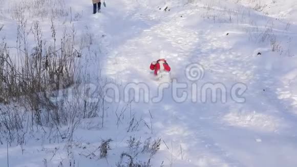 穿着红色夹克和带围巾的白色帽子的女孩从雪山上下来把雪拉下来寒假视频的预览图