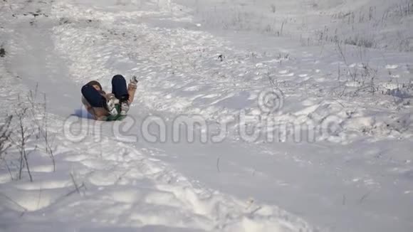 小女孩乘雪橇滑下山冬天在圣诞公园玩的女孩慢动作视频的预览图