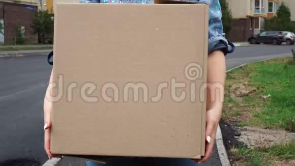 年轻女子背着一个纸板箱在户外散步视频的预览图