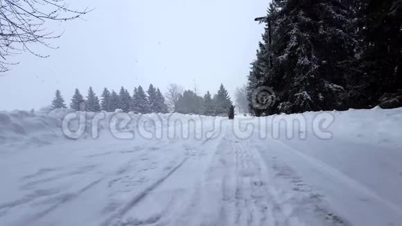 家长拉着孩子在冬天雪橇远离相机进入背景雪景景观中的家庭场景下雪了视频的预览图