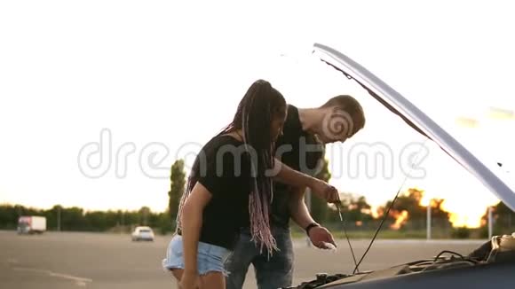 一对年轻夫妇的侧视图停在了停车场的路上穿黑色T恤的年轻人检查机油视频的预览图