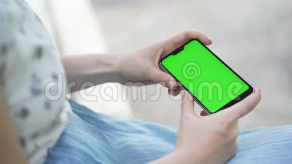 漂亮的女孩手里拿着一个绿色屏幕的智能手机视频的预览图