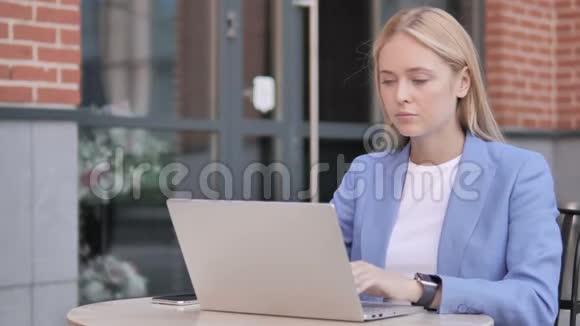 头痛的女商人用笔记本电脑坐在户外视频的预览图