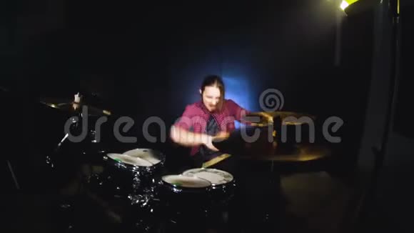 这位长发鼓手在一个黑色背景的黑暗房间里演奏完鼓摇滚音乐家宽角度视频的预览图