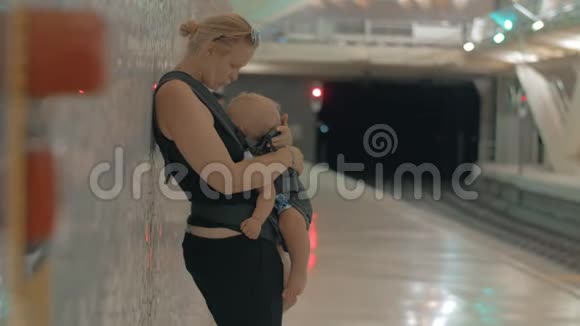 妈妈和熟睡的孩子在地下等火车视频的预览图