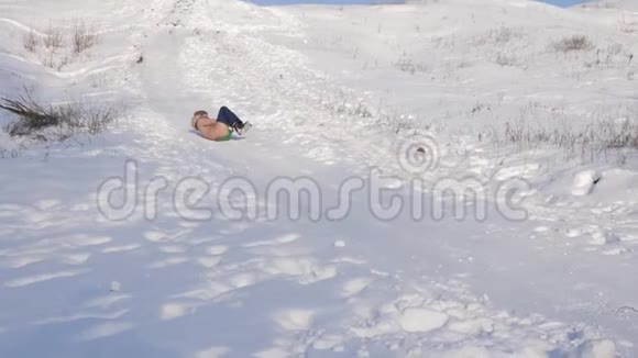 冬天快乐的女孩从雪山上滚过白雪微笑着慢动作视频的预览图