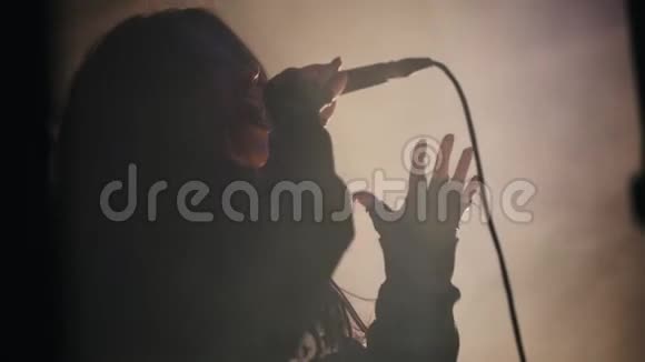 一位女歌手在烟雾弥漫的舞台上用麦克风演唱视频的预览图