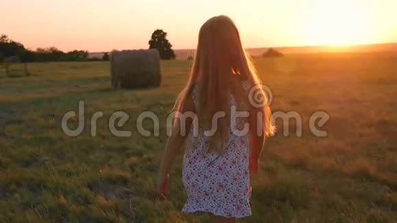 日落时分在草地上散步的漂亮女孩视频的预览图