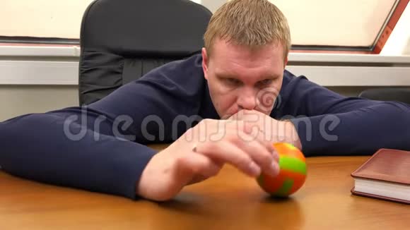 一个办公室工作人员若有所思地把一个小球滚过桌子视频的预览图