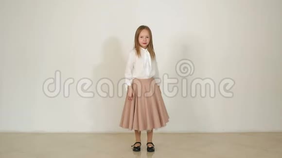 一个可爱的小女孩穿着长裙跳跃在白色的背景上玩得很开心视频的预览图
