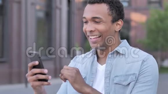 户外非洲男人在电话上为成功而兴奋视频的预览图