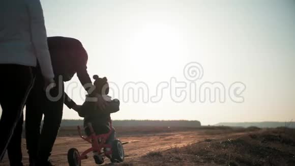 日落时分剪影一家人在一起小男孩学骑自行车爸爸教儿子骑自行车视频的预览图