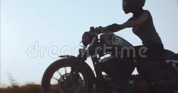 女孩驾驶摩托车在日落时沿着乡间小路行驶视频的预览图