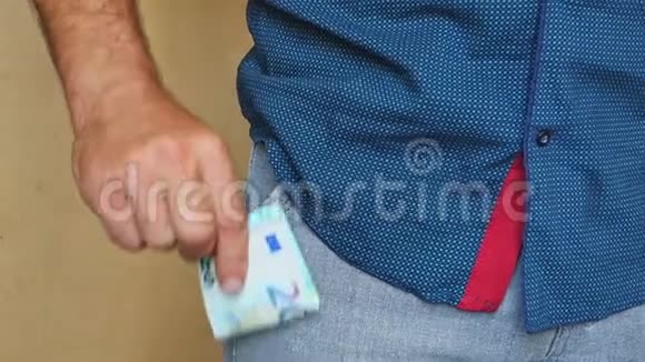 一个男人把欧元钞票放进裤兜里一个人把钱藏在口袋里视频的预览图