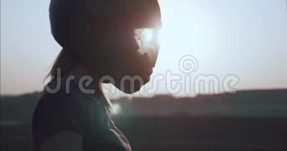 一个戴着头盔的女孩在夕阳下的肖像背光侧视视频的预览图