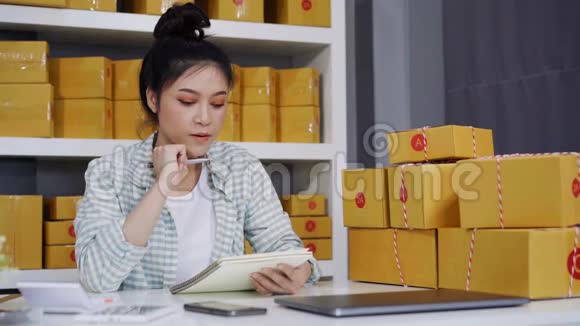 年轻女性企业家在自己的工作中在网上购物数着包裹盒视频的预览图