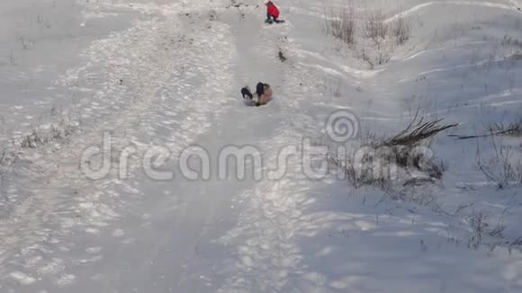 冬天快乐的女孩从雪山上滚过白雪微笑着慢动作视频的预览图