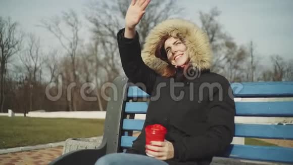 肖像微笑的年轻女子拿着一杯茶或咖啡喝着寒冷阳光下的户外视频的预览图