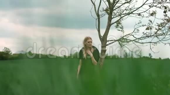 美丽金发的肖像女孩站在树下视频的预览图