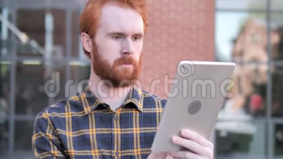 红胡子青年使用平板户外视频的预览图