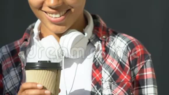 戴着耳机喝着咖啡微笑着大城市生活的美女视频的预览图