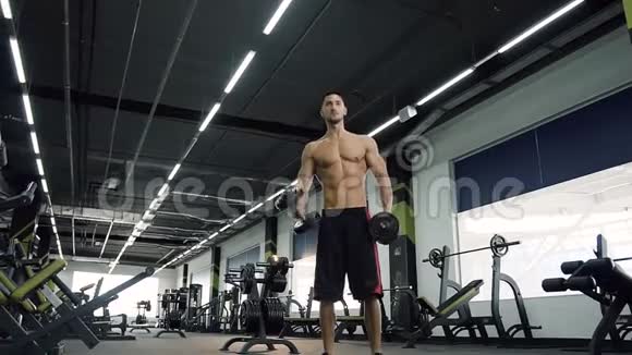 很有魅力的运动男孩在健身房用哑铃锻炼视频的预览图