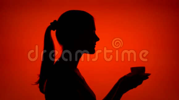 红色背景上有一杯咖啡的女人剪影女性的脸侧脸喝咖啡视频的预览图