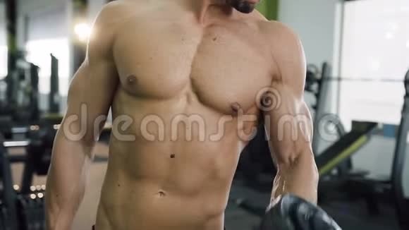强壮的男人赤裸的躯干用哑铃在健身房里抽肌肉手臂视频的预览图