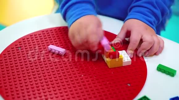 用五颜六色的塑料块在桌子上盖上小孩子的手视频的预览图