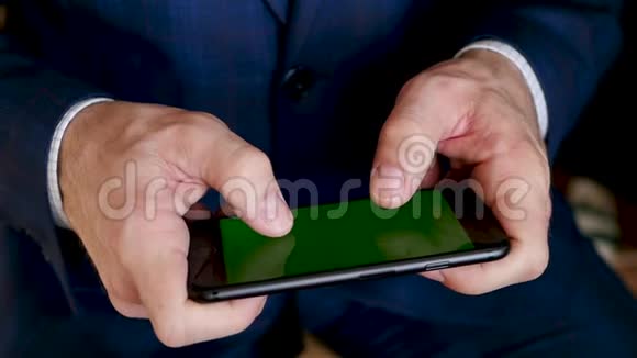 一个商人正在用绿色屏幕智能手机在黑色背景下慢动作视频的预览图