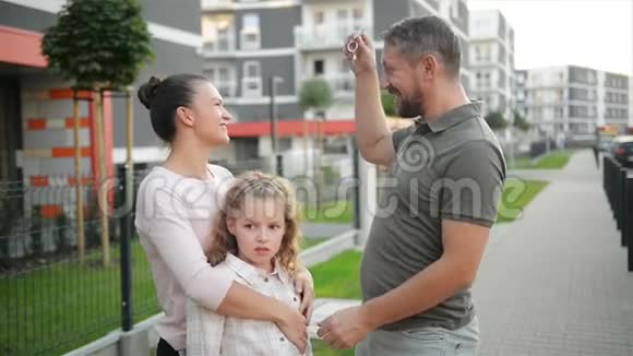 幸福的家庭与孩子站在户外持有钥匙的大乡村之家微笑豪华房地产业主夫妇视频的预览图