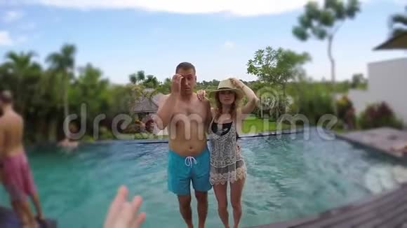 年轻可爱的夫妇在热带度假别墅拍照并掉进游泳池视频的预览图