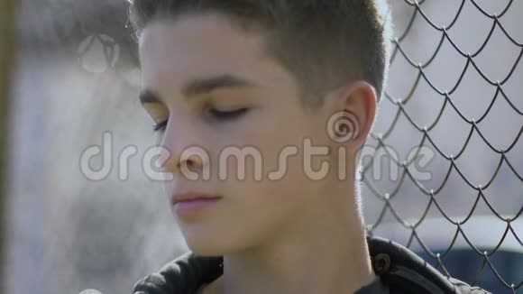 十几岁的男孩靠在铁栅栏上想着他的未来少年殖民地视频的预览图