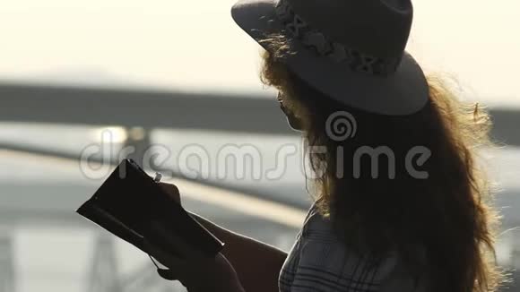 女人在笔记本上写在桥上看日出视频的预览图