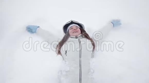 一个年轻的女孩在冬天和雪地里快乐在冬天的公园里玩耍不躺在雪地里视频的预览图