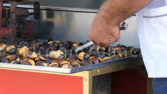 男售货员正在市街做烤栗子街上的食物热熟的栗子视频的预览图