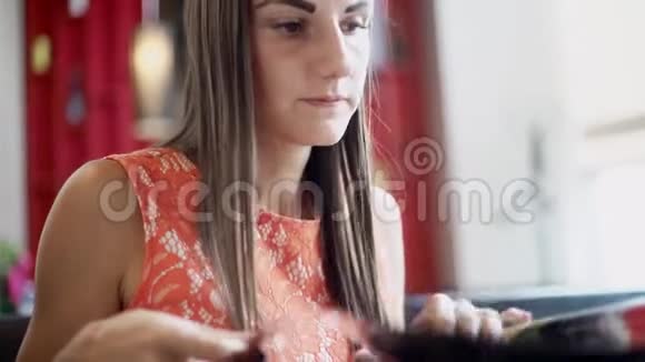 可爱的女性在一家咖啡馆里手里拿着菜单一个女人在菜单上选择食物和饮料来点菜视频的预览图