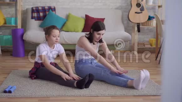 妈妈和女儿坐在地板上做伸展运动视频的预览图
