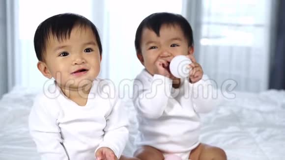 欢快的双胞胎宝宝在床上玩彩球视频的预览图