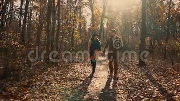 年轻女子白天和男朋友在风景如画的秋林散步视频的预览图