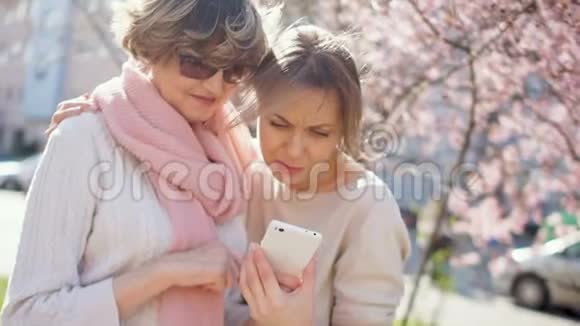 两个女人和一个智能手机年轻女子教成熟的人使用智能手机视频的预览图