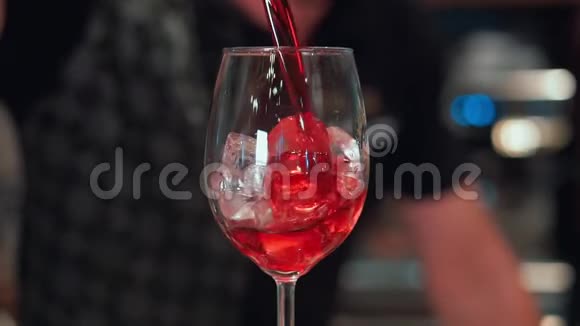在夜总会或酒吧酒保准备加冰和葡萄酒的鸡尾酒红酒流入酒杯慢速运动视频的预览图