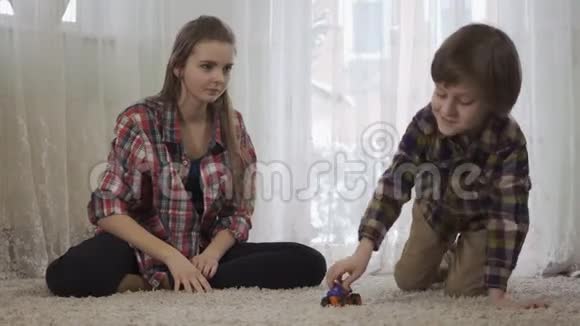 姐姐和弟弟一起玩坐在地板上毛茸茸的地毯上那个男孩在玩视频的预览图