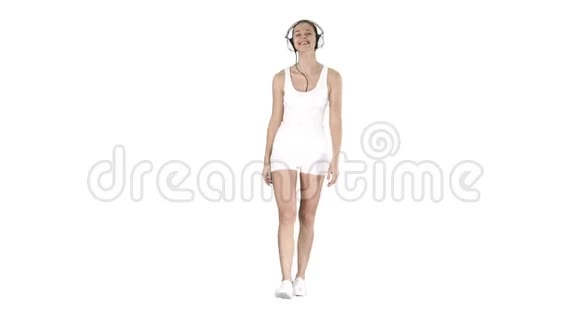 迷人的健身女孩在白色背景下散步和听音乐视频的预览图