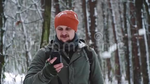 一个人在雪地森林里用手机社交网络看视频下注笑和高兴微笑面对视频的预览图