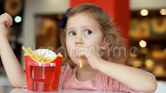 小女孩在咖啡馆里吃快餐薯条和喝果汁肖像特写视频的预览图